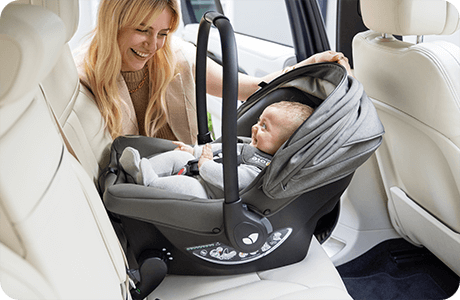 Baby in Sprint infant carrier being installed into back seat of car by happy mother