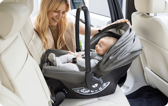 Baby in Sprint infant carrier being installed into back seat of car by happy mother